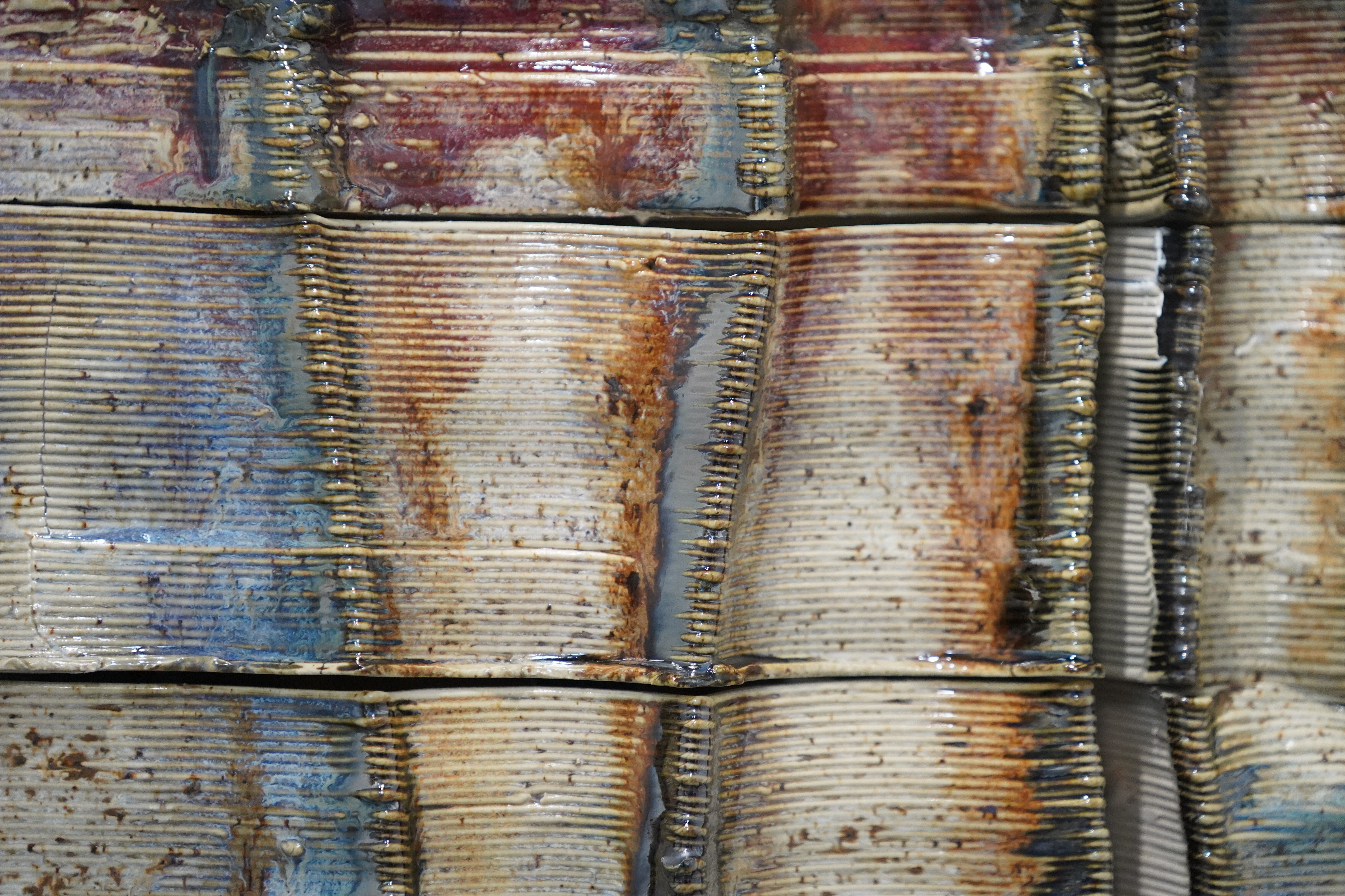 Fired ceramic façade — printed clay glazed into an earth-toned palette